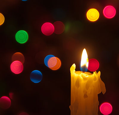 candle in front of Christmas tree lights, photo by Flickr user LenDog64